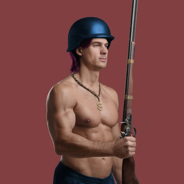 Muscular guy with chain and naked torso holding rifle — Foto Stock
