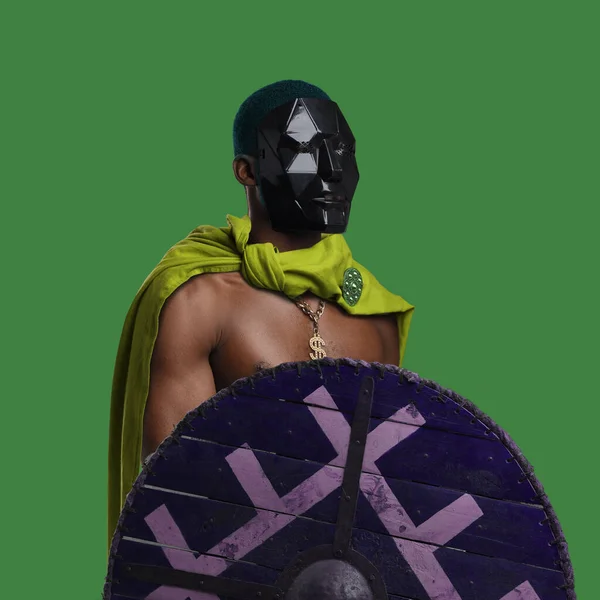 African man with cape and shield against green background — Stock Photo, Image