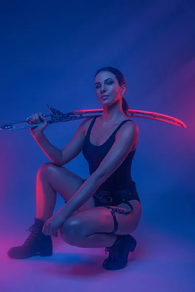 Mulher estilo cyberpunk com espada contra fundo azul — Fotografia de Stock