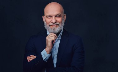 Mutlu ve düşünceli yaşlı adam karanlık arka plana karşı poz veriyor.