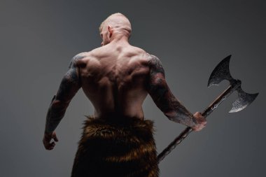 Çelik baltayla dövmeli Viking sırtı kameraya dönük.