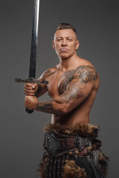 Красивый воин с мускулистым телосложением и мечом, смотрящим в камеру — стоковое фото