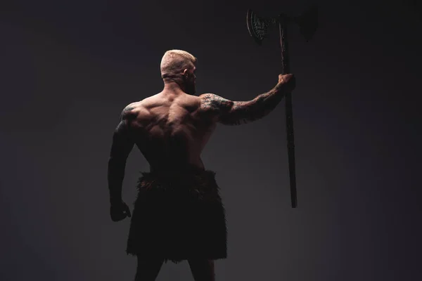 Tattooed viking with steel axe his back facing to camera — Stock Photo, Image