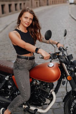 Kahverengi saçlı kadın dışarıda eski moda motosiklet kullanıyor.
