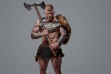 Omzunda iki el baltası tutan dövmeli kaslı Viking.