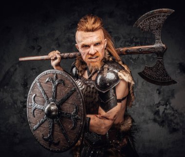 Barbaric viking with shield and axe on his shoulder clipart