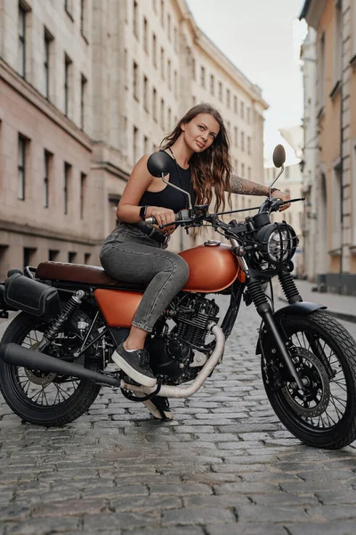 Braunhaarige Frau fährt altmodisches Motorrad im Freien — Stockfoto