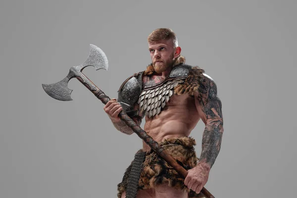 Handsome northern warrior holding axe against gray background — Stock Photo, Image