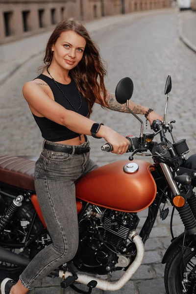 Коричневая женщина на старомодном мотоцикле на открытом воздухе — стоковое фото