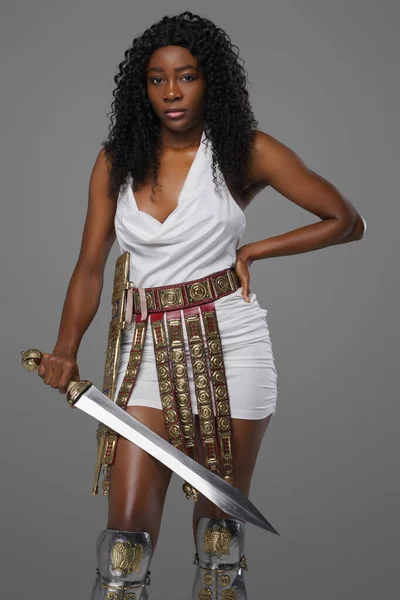 Античная черная женщина-воин держит гладиуса на сером фоне — стоковое фото