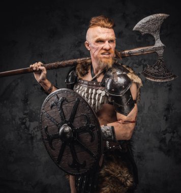 Kızgın kızıl saçlı viking omzunda baltayla başka tarafa bakıyor.