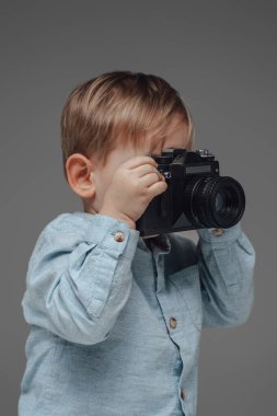 Gri arka planda kameralı neşeli çocuk fotoğrafçısı