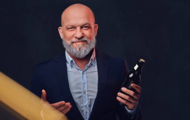 Siyah arka planda şişesi olan şık yaşlı bir adam.