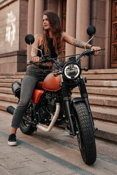 Motociclista mujer de moda posando en motocicleta de estilo retro al aire libre — Foto de Stock