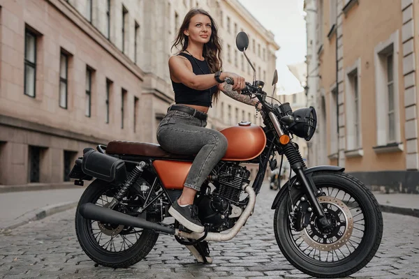 Hnědé vlasy žena na koni staromódní motobike venku — Stock fotografie