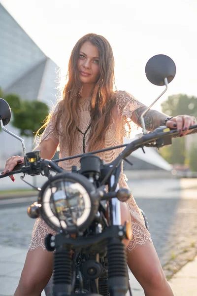 Aantrekkelijke vrouwelijke biker met tatoeages zittend op retro motor — Stockfoto