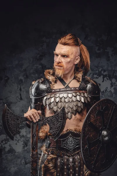 Viking poseren met schild en bijl tegen donkere achtergrond — Stockfoto