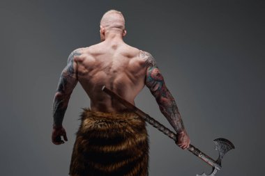 Çelik baltayla dövmeli Viking sırtı kameraya dönük.