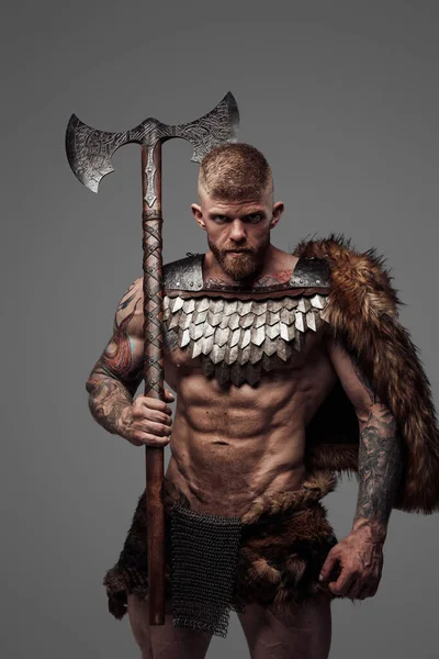 Tatuado muscular viking segurando duas mãos machado em seu ombro — Fotografia de Stock