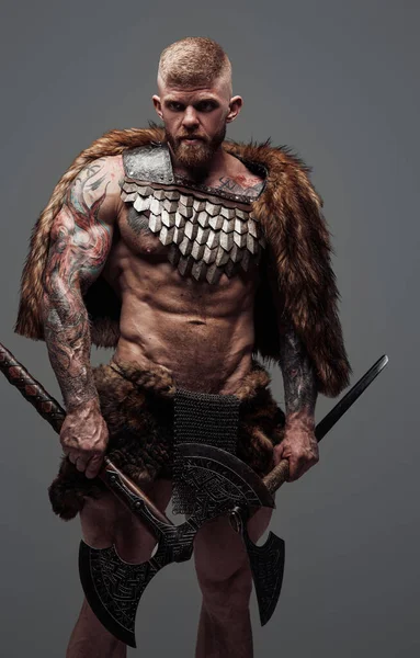 Яростный викинг, одетый в мех и доспехи с двумя топорами — стоковое фото