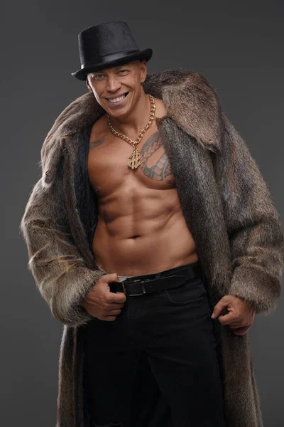 Hombre musculoso de moda vestido con abrigo de piel y sombrero — Foto de Stock