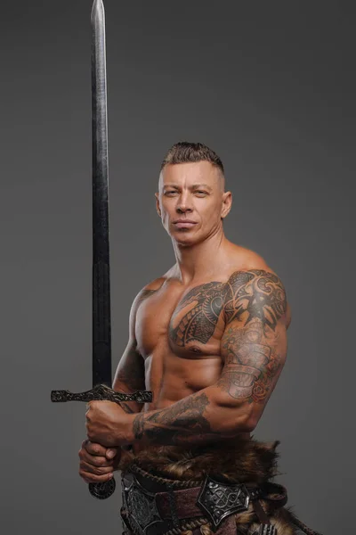 Spierkrijger met naakte romp met zwaard tegen grijze achtergrond — Stockfoto
