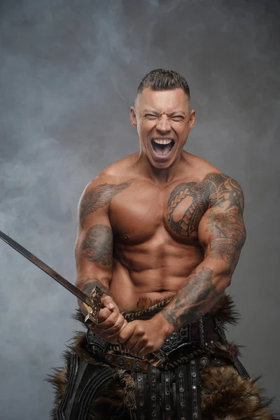 Guerrero furioso con espada contra fondo con humo — Foto de Stock