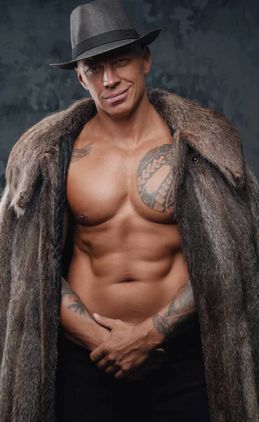 Smiling bodybuilder dressed in top hat and fur coat — Stock Photo, Image