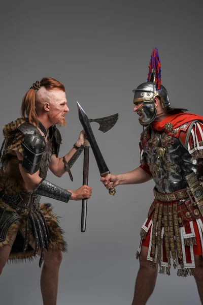 Schot van gewelddadige viking en Romeinse soldaat tegen grijze achtergrond — Stockfoto