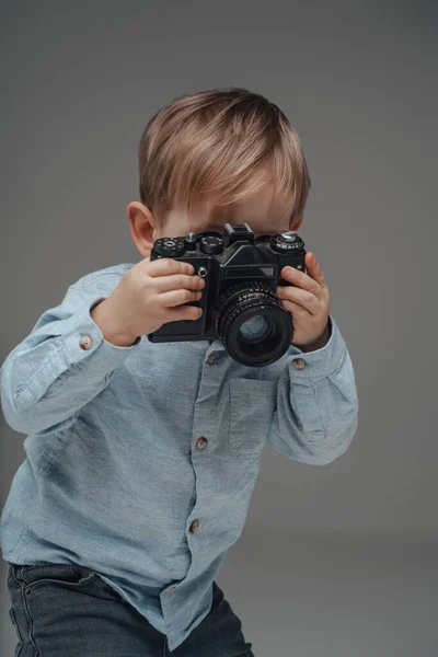 带着灰色背景相机的快乐的儿童摄影师 — 图库照片