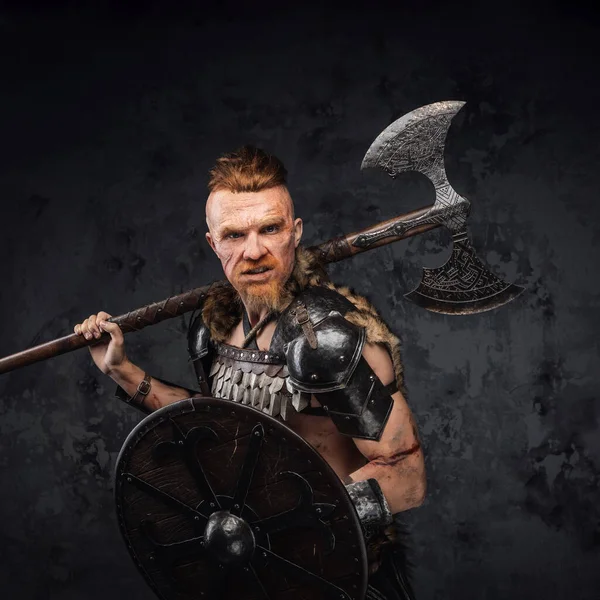 Woedende roodharige viking met bijl op zijn schouder kijkend naar camera — Stockfoto