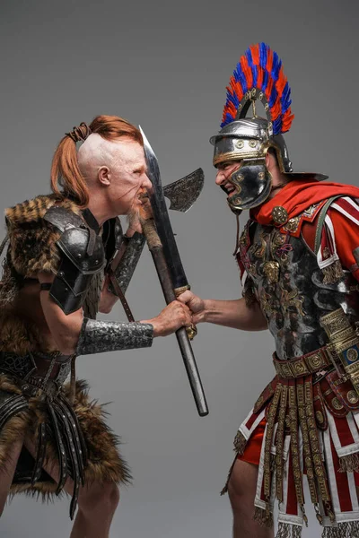 Tiro de violento vikingo y soldado romano sobre fondo gris —  Fotos de Stock