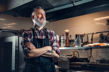 Mutfaktaki yaşlı aşçı adam yemeği düşünüyor.