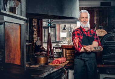 Önlüğü ve pişmemiş eti olan yaşlı bir et dükkânı çalışanı.