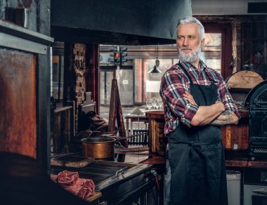 Kendine güveni tam yaşlı bir adam et bakkalında klasik tarzda poz veriyor.