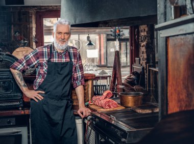 Gri saçlı kasap ve eski moda et dükkanındaki işi.