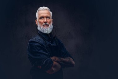 Önlüklü kendinden emin yaşlı kasap çapraz kollarla poz veriyor.