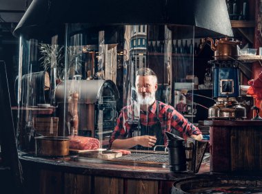 Yaşlı şef kasada oturmuş et dükkanında et hazırlıyor.