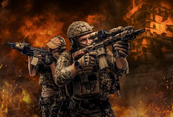 Dwóch dumnych żołnierzy z wycelowanymi karabinami przeciwko płonącemu miastu. — Zdjęcie stockowe