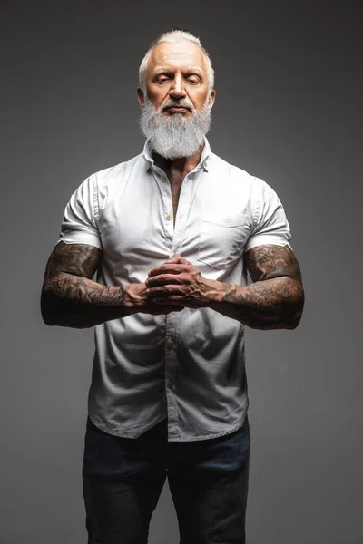 Homem idoso com corpo tatuado posando contra fundo cinza — Fotografia de Stock