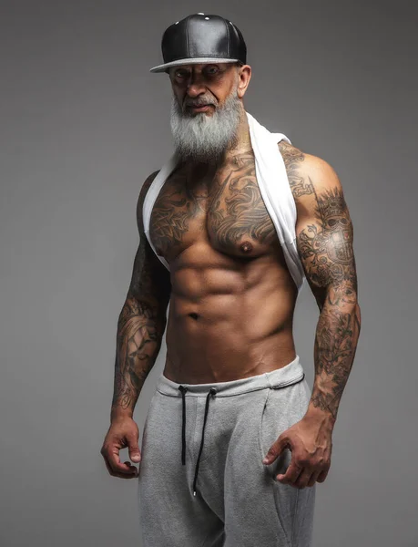 Musculoso anciano vestido con ropa deportiva sobre fondo gris —  Fotos de Stock