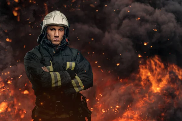 Fireman with crossed arms posing against flame and explosions — Stock Photo, Image