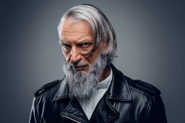 Deri ceketli yaşlı motosikletçi kameraya bakıyor.