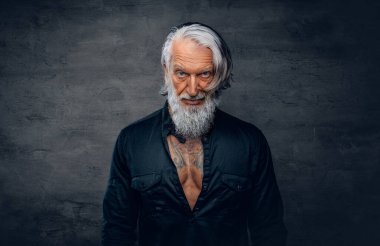 Siyah gömlekli, esmer, yakışıklı yaşlı bir adam.