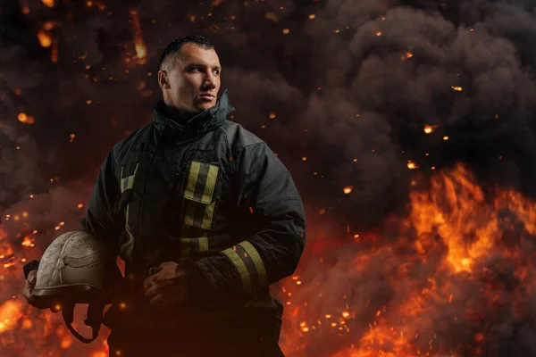 Pompiere che distoglie lo sguardo con cappello duro contro fiamme ed esplosioni — Foto Stock