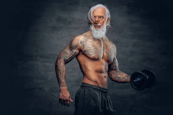 Bearded vieil homme bodybuilder avec tatouages tenant haltère — Photo