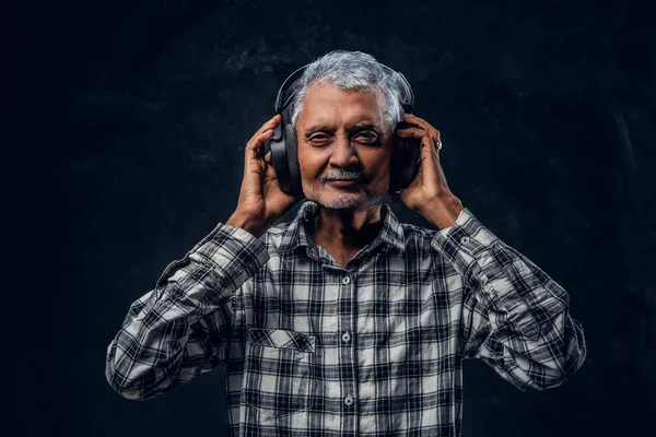 Hombre viejo alegre con auriculares vestidos con camisa a cuadros — Foto de Stock