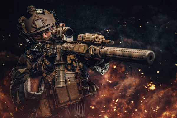 Bojovný voják mířící puškou proti tmavému pozadí s explozí — Stock fotografie