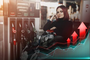 Fiyatlarda artış. Benzin istasyonunda motosiklette oturan kızıl saçlı kadın.