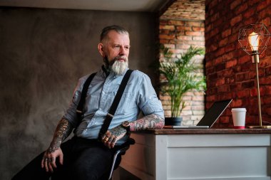 Üst düzey işadamı masada dizüstü bilgisayarla oturuyor.